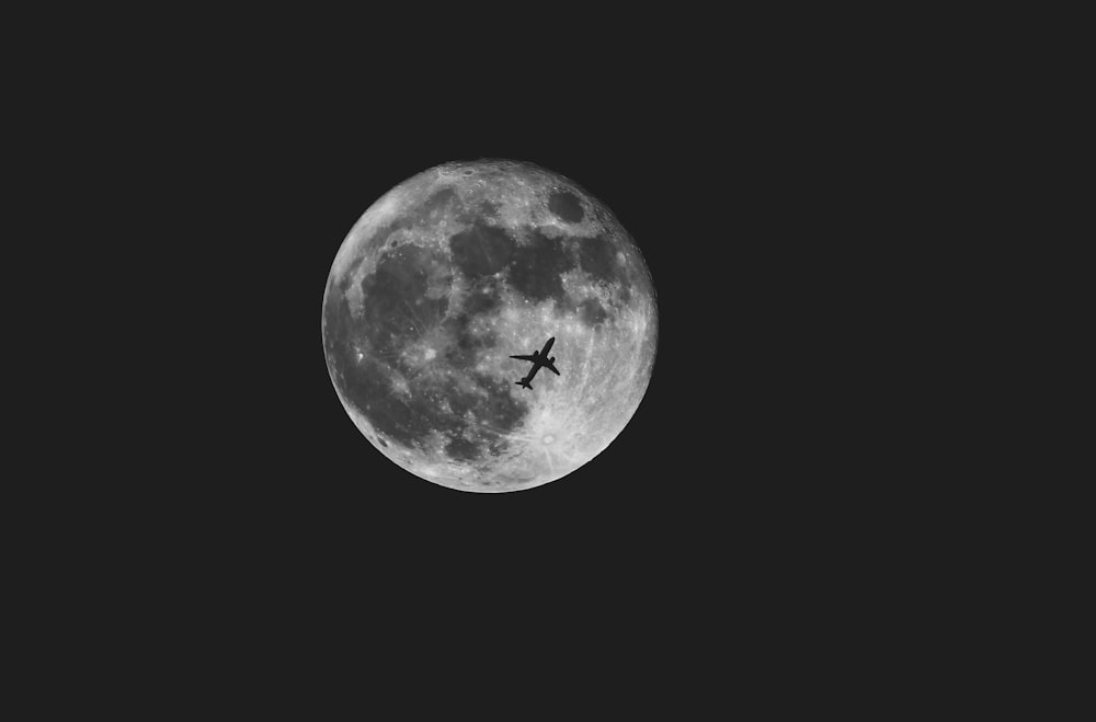 an airplane flying in front of a full moon