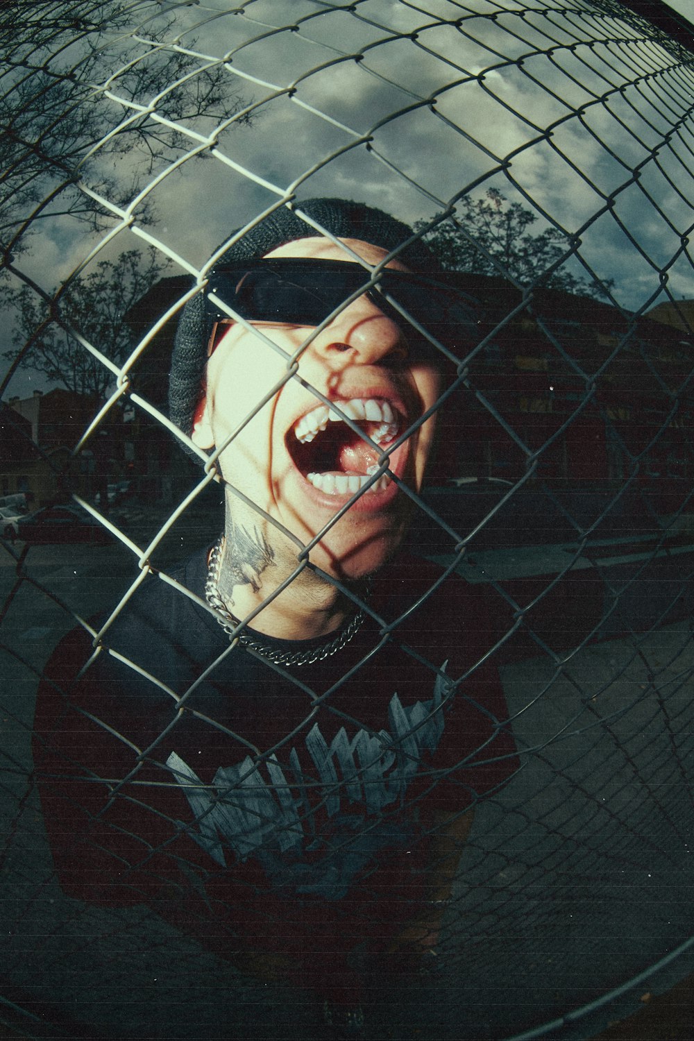 a man with his mouth open behind a wire fence