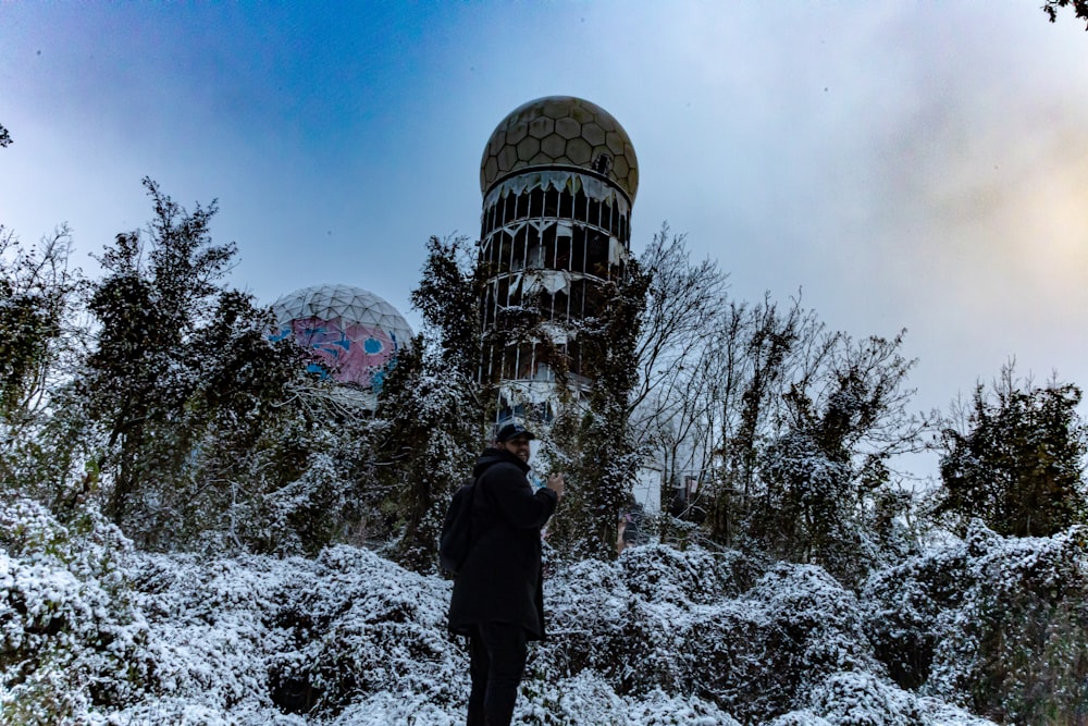 a man standing in the snow in front of a building