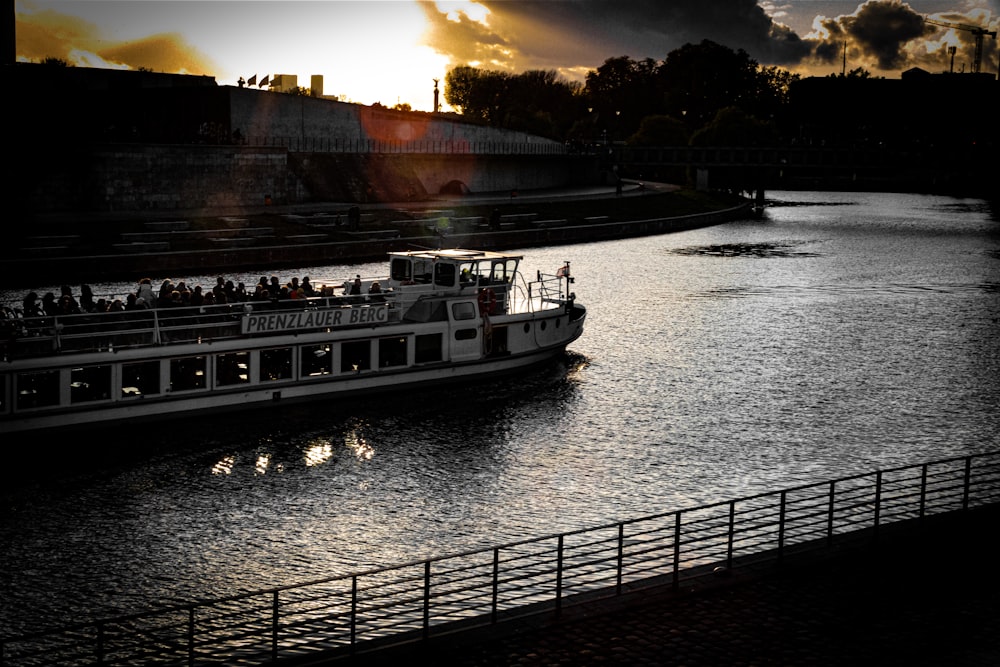 a large boat traveling down a river under a cloudy sky