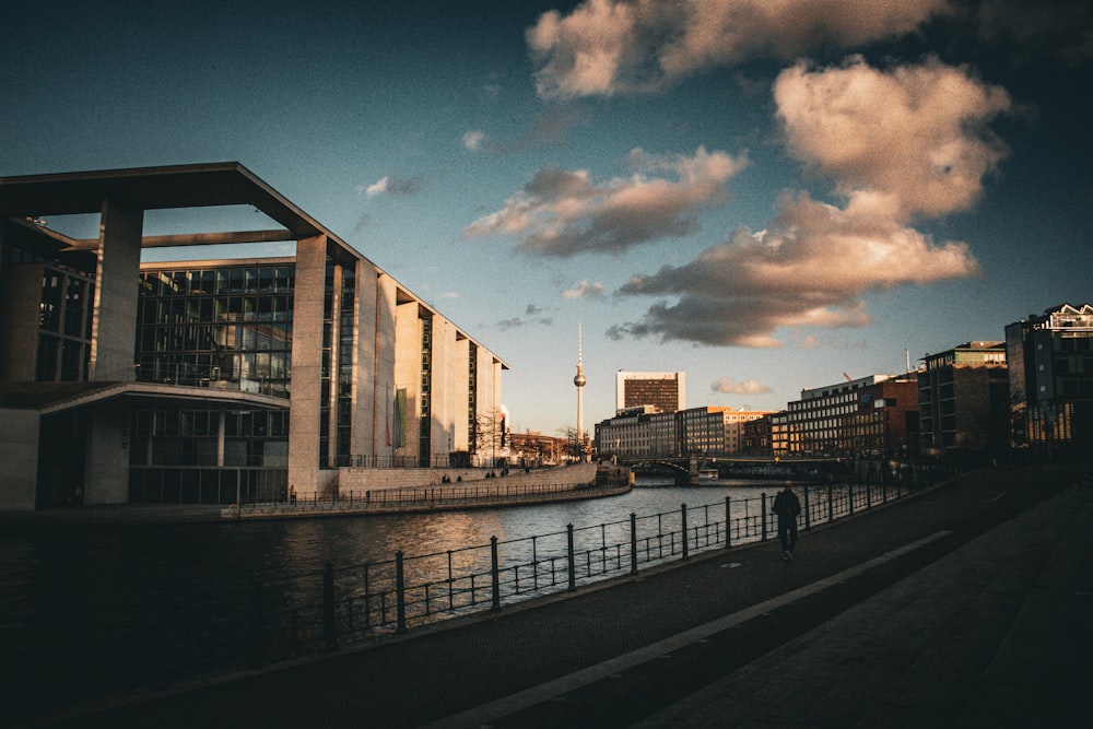 a man walking down a sidewalk next to a body of water