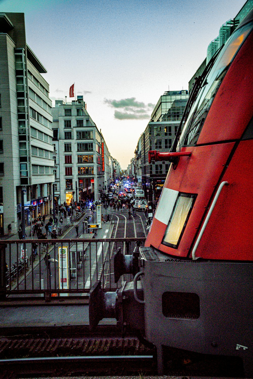 a red train traveling down train tracks next to tall buildings