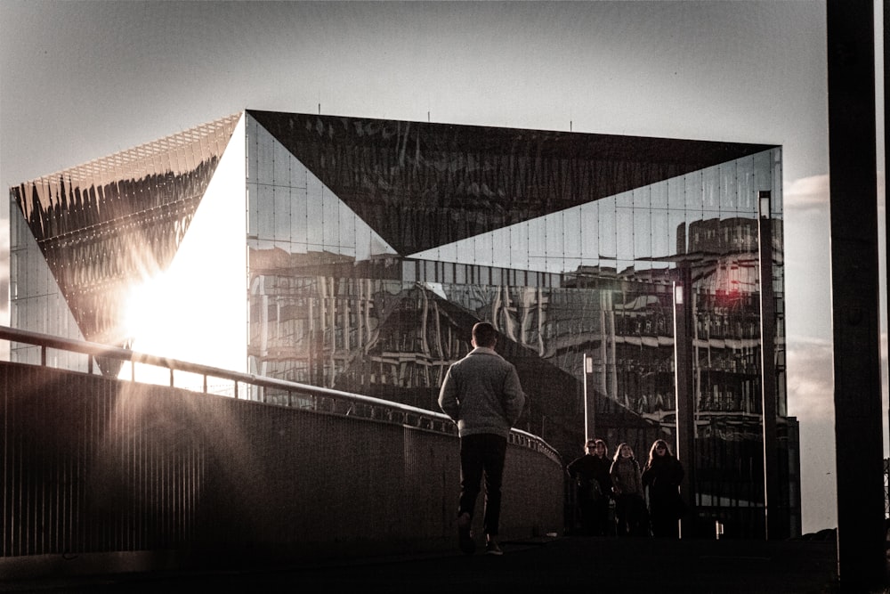 a man walking down a sidewalk next to a tall building