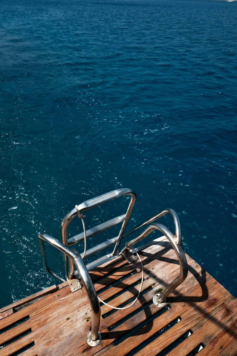 a metal chair sitting on top of a wooden dock
