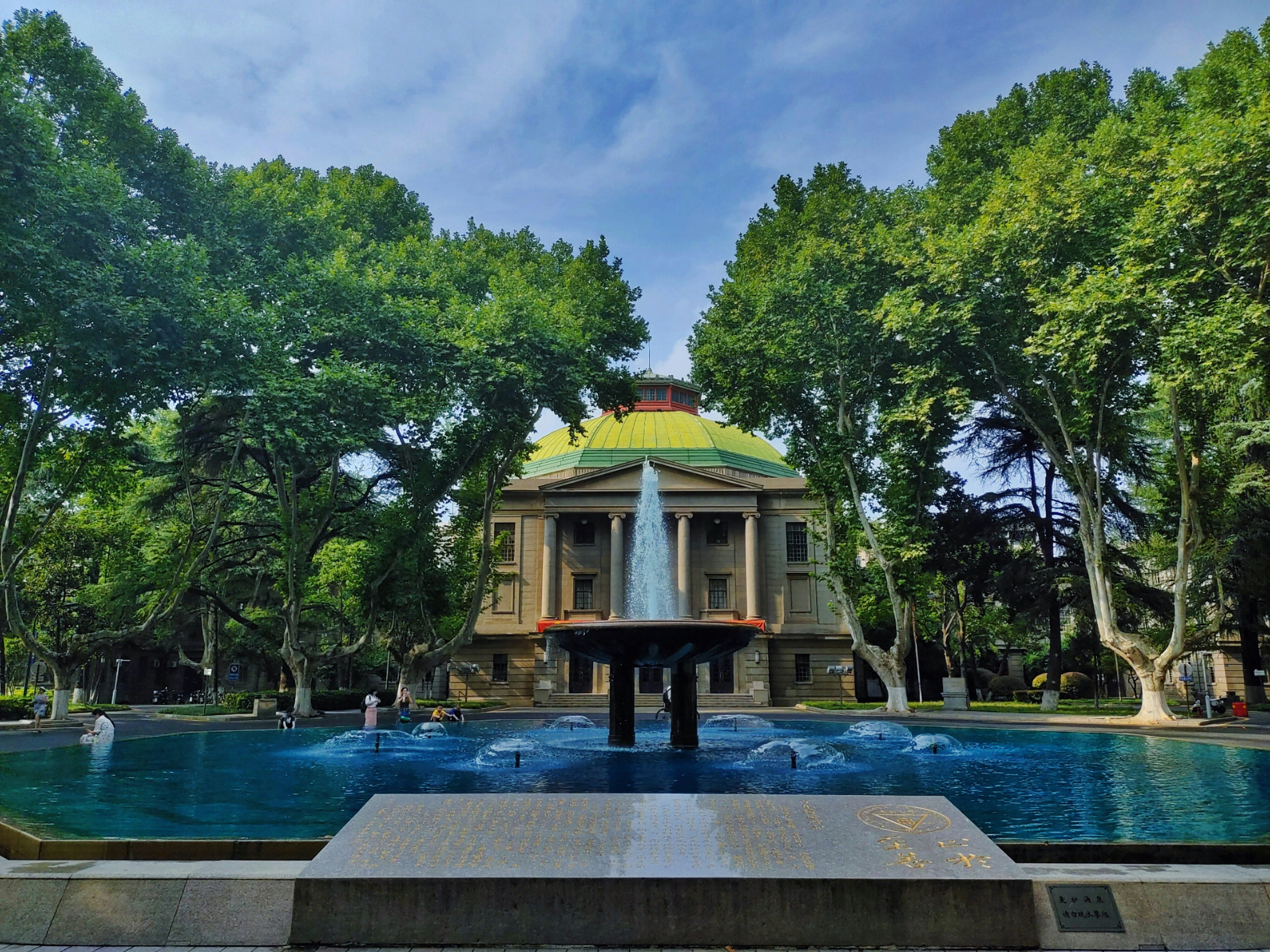A fountain in the middle of a park surrounded by trees photo – Free ...
