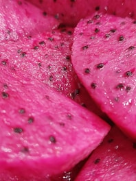 Close-up of a freshly cut ruby red dragon fruit showing its vivid red interior and tiny black seeds.