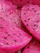 Close-up of a vibrant pink dragon fruit sliced open, showcasing its speckled white flesh and black seeds on a clean white background.