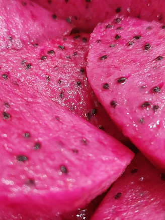 Close-up of a ripe pitahaya fruit sliced open showing vibrant pink flesh and seeds