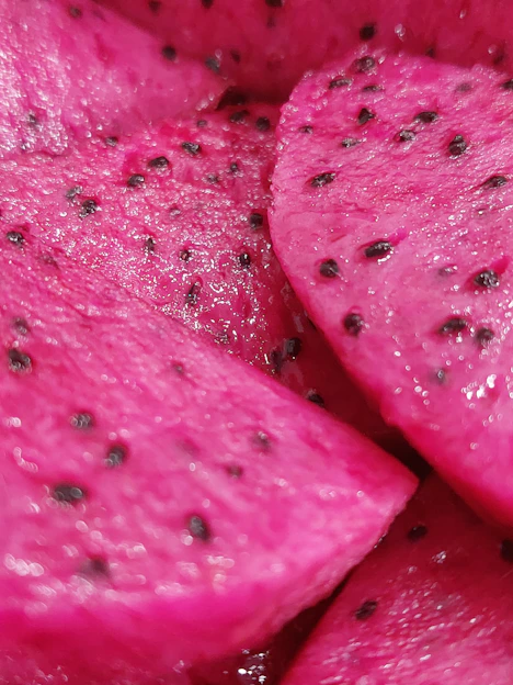 Close-up of a ripe pitahaya fruit sliced open showing vibrant pink flesh and seeds