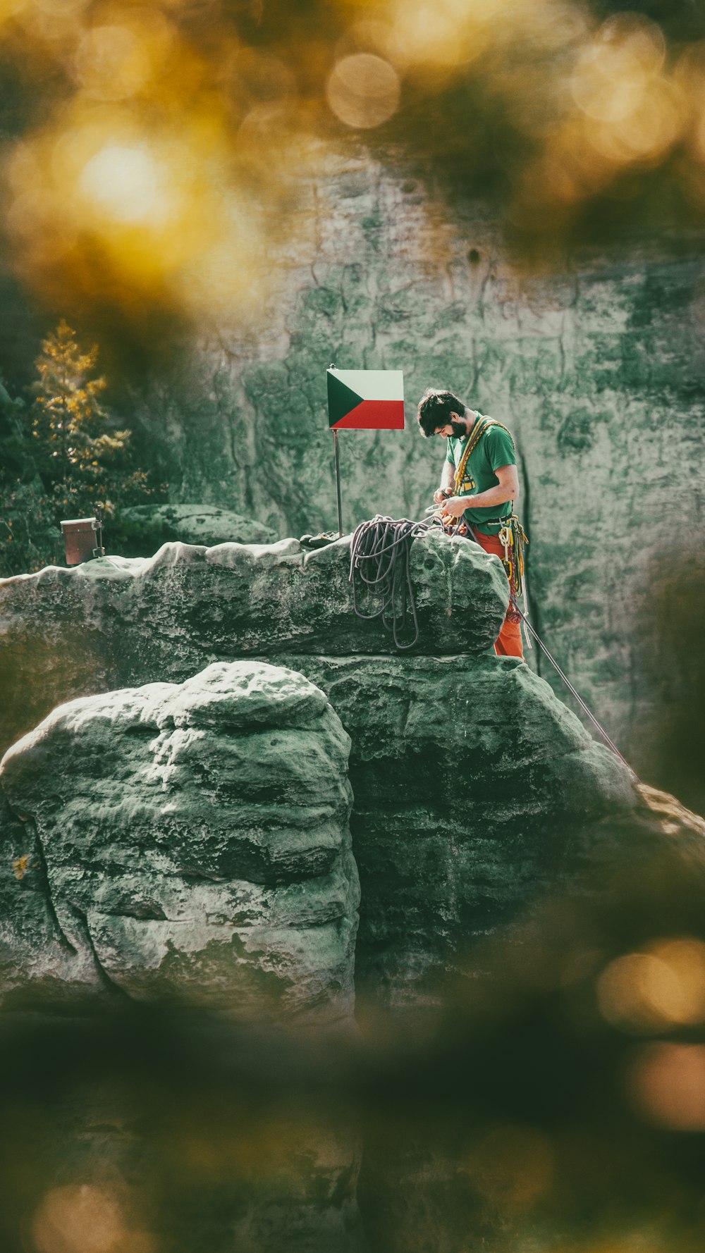 a man sitting on top of a rock next to a flag