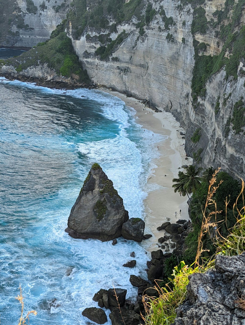a rocky cliff overlooks the ocean and beach