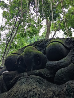 A ceramic sculpture resembling a mythical creature emerging from moss-covered roots.