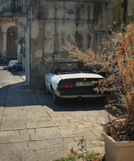 A gleaming restored vintage convertible parked under the warm Mallorcan sun beside a cobblestone street.