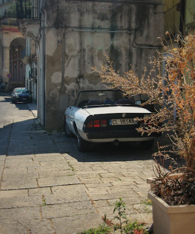 A gleaming restored vintage convertible parked under the warm Mallorcan sun beside a cobblestone street.
