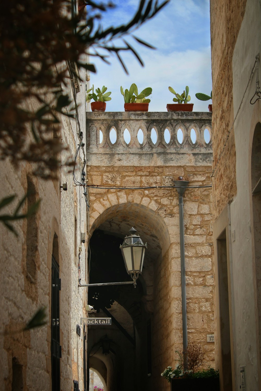 a narrow alley with a lamp post and potted plants
