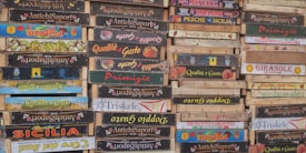 A stack of wooden crates with various Italian brand labels and colorful designs indicating different product origins and companies.