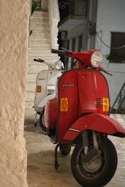 a red scooter parked next to a white scooter