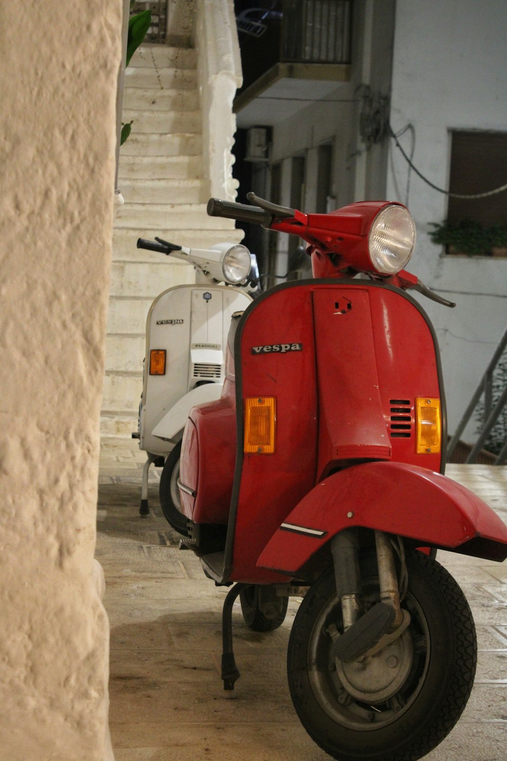 a red scooter parked next to a white scooter
