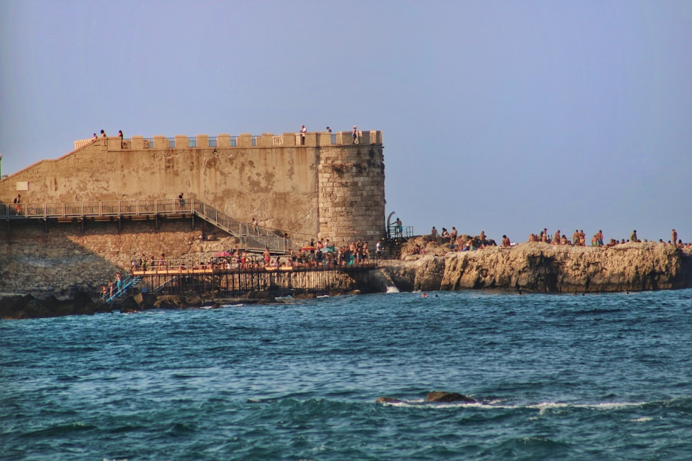 a group of people standing on top of a cliff next to a body of water