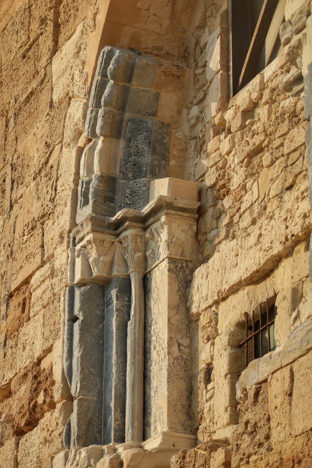 a tall stone building with a window on the side of it