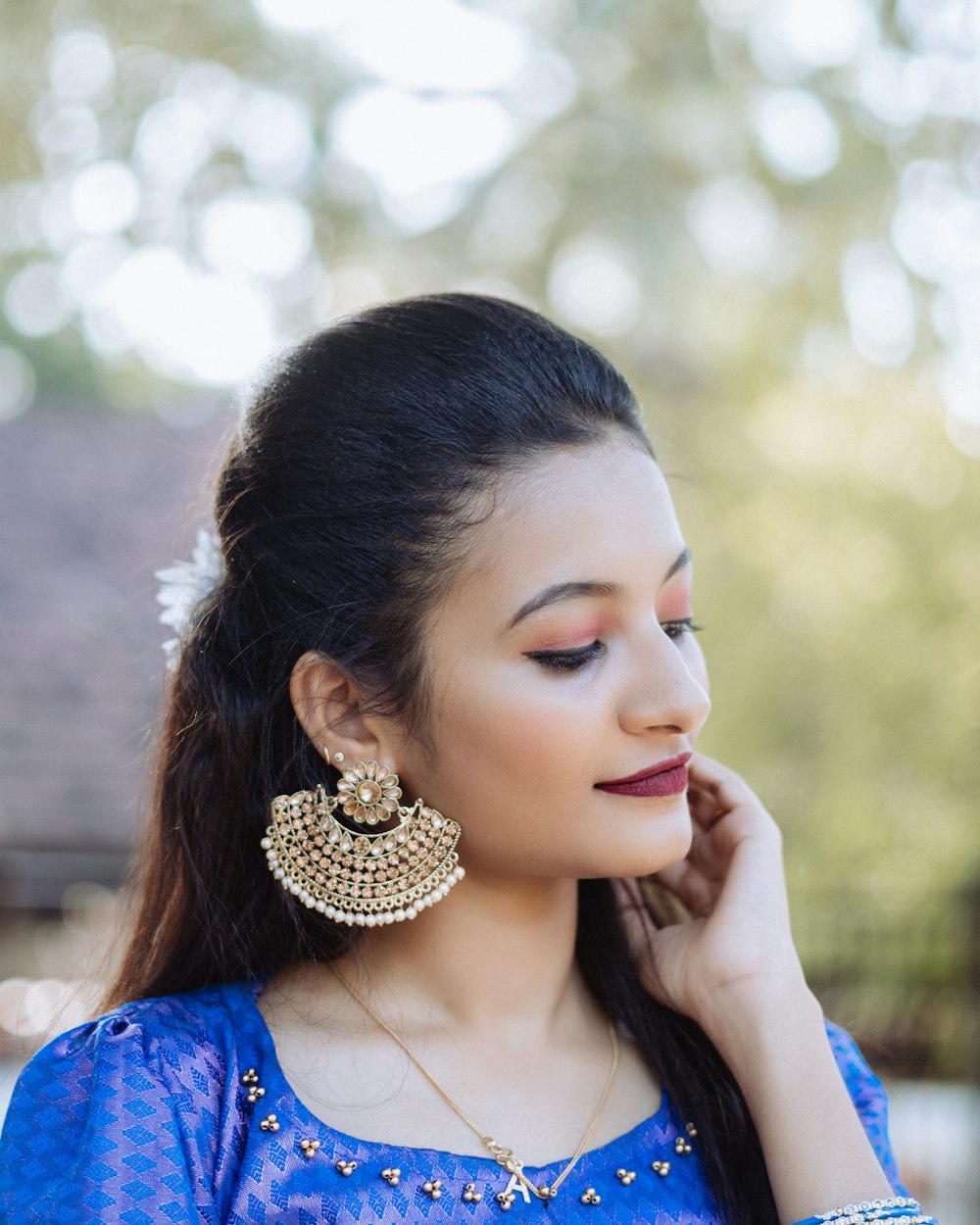 a woman wearing a blue blouse and gold earrings