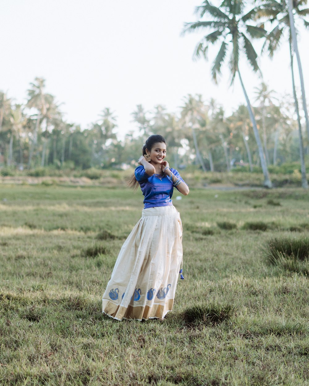 a woman in a blue top and white skirt in a field