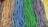 An assortment of colorful, sugar-coated candy strips is lined up in bundles. Each bundle consists of braids of different colors, including rainbow, blue, green, purple, and yellow.