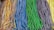An assortment of colorful, sugar-coated candy strips is lined up in bundles. Each bundle consists of braids of different colors, including rainbow, blue, green, purple, and yellow.