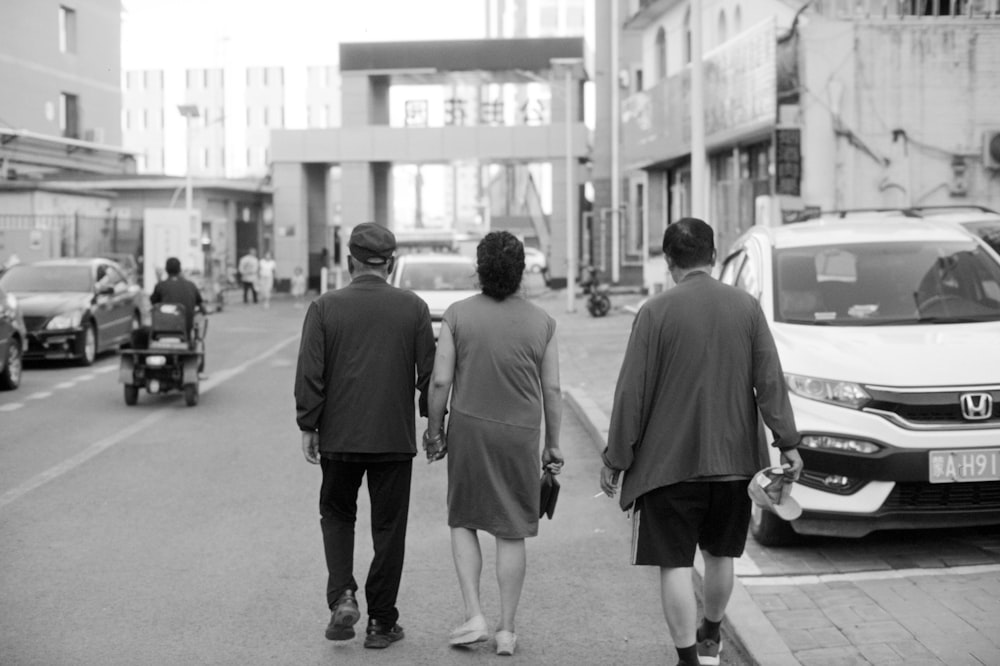 three people walking down a street holding hands