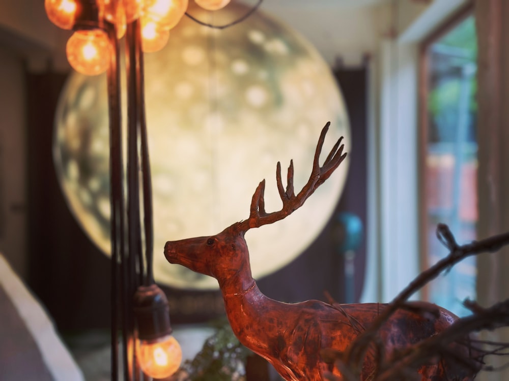 a deer statue sitting on top of a table next to a lamp