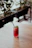 Refreshing glass of hibiscus iced tea with ice cubes and a sprig of mint on a wooden table outdoors.
