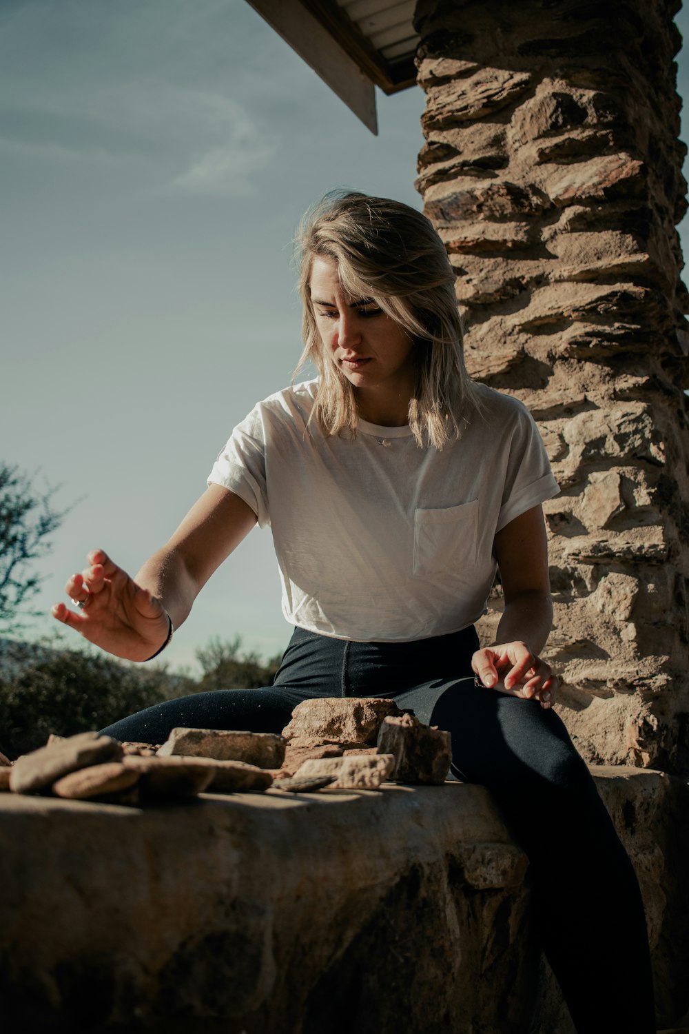 a woman is sitting on a rock outside