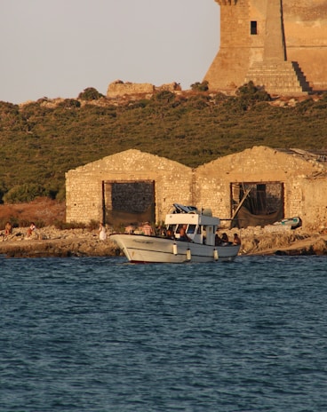 A cozy motorboat anchored near a quiet cove with rocky cliffs and pine trees on Mallorca island.