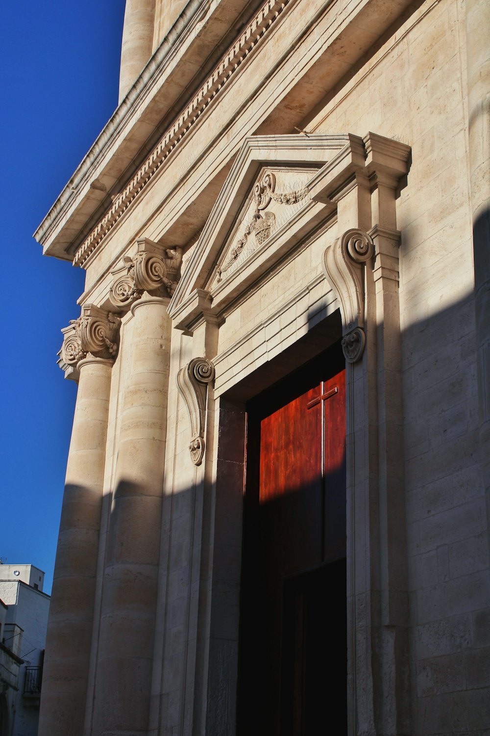 a tall building with a red door and a clock on it's side