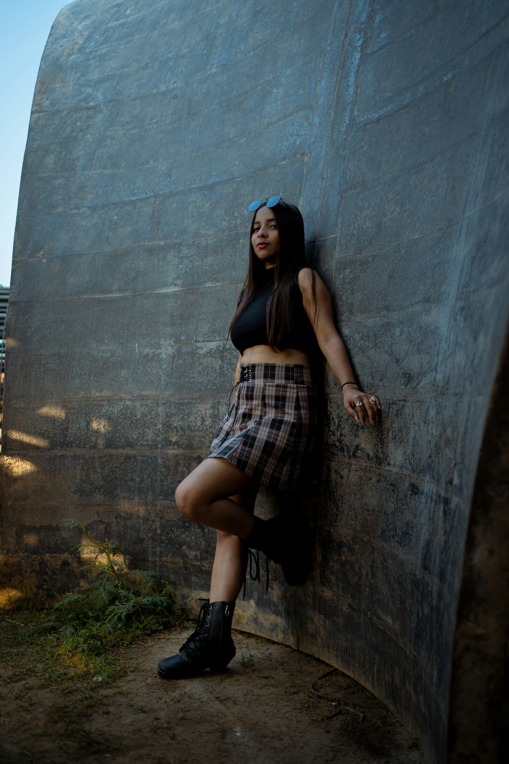 a woman leaning against a wall wearing a skirt