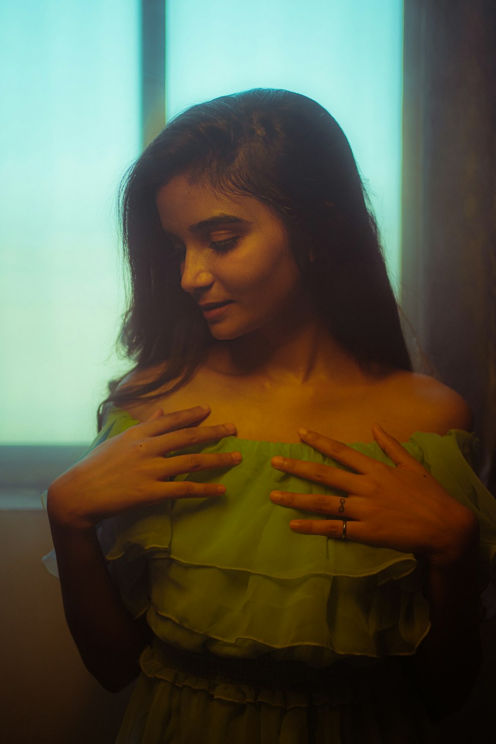 a woman in a green dress is holding her hands on her chest