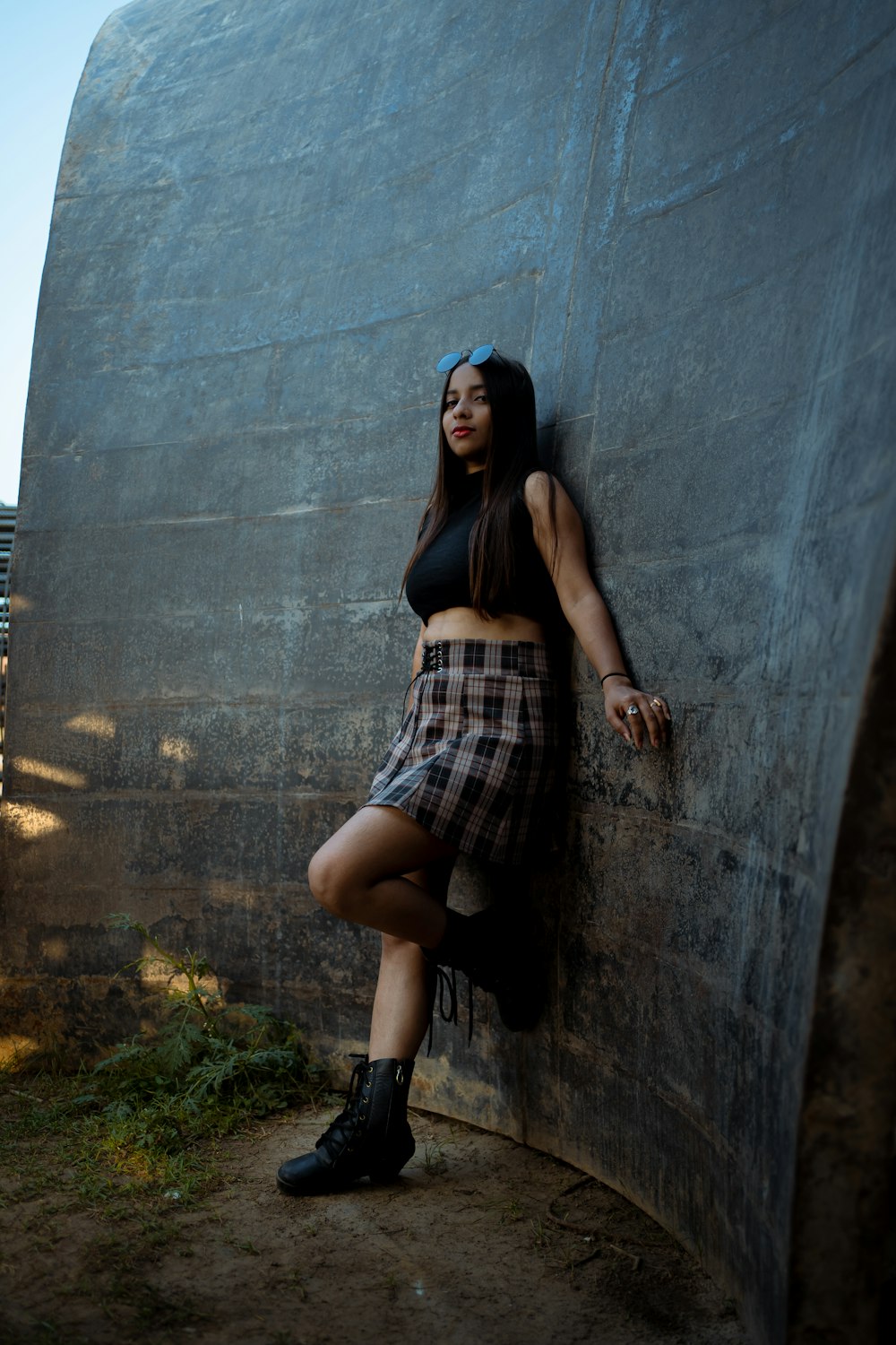 a woman leaning against a wall wearing a skirt