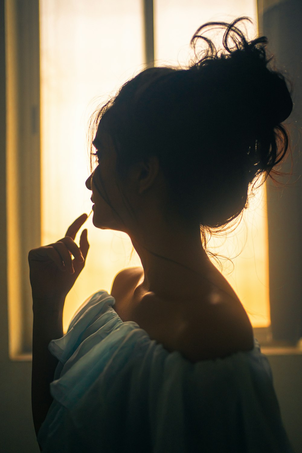 a woman standing in front of a window with her finger in her mouth