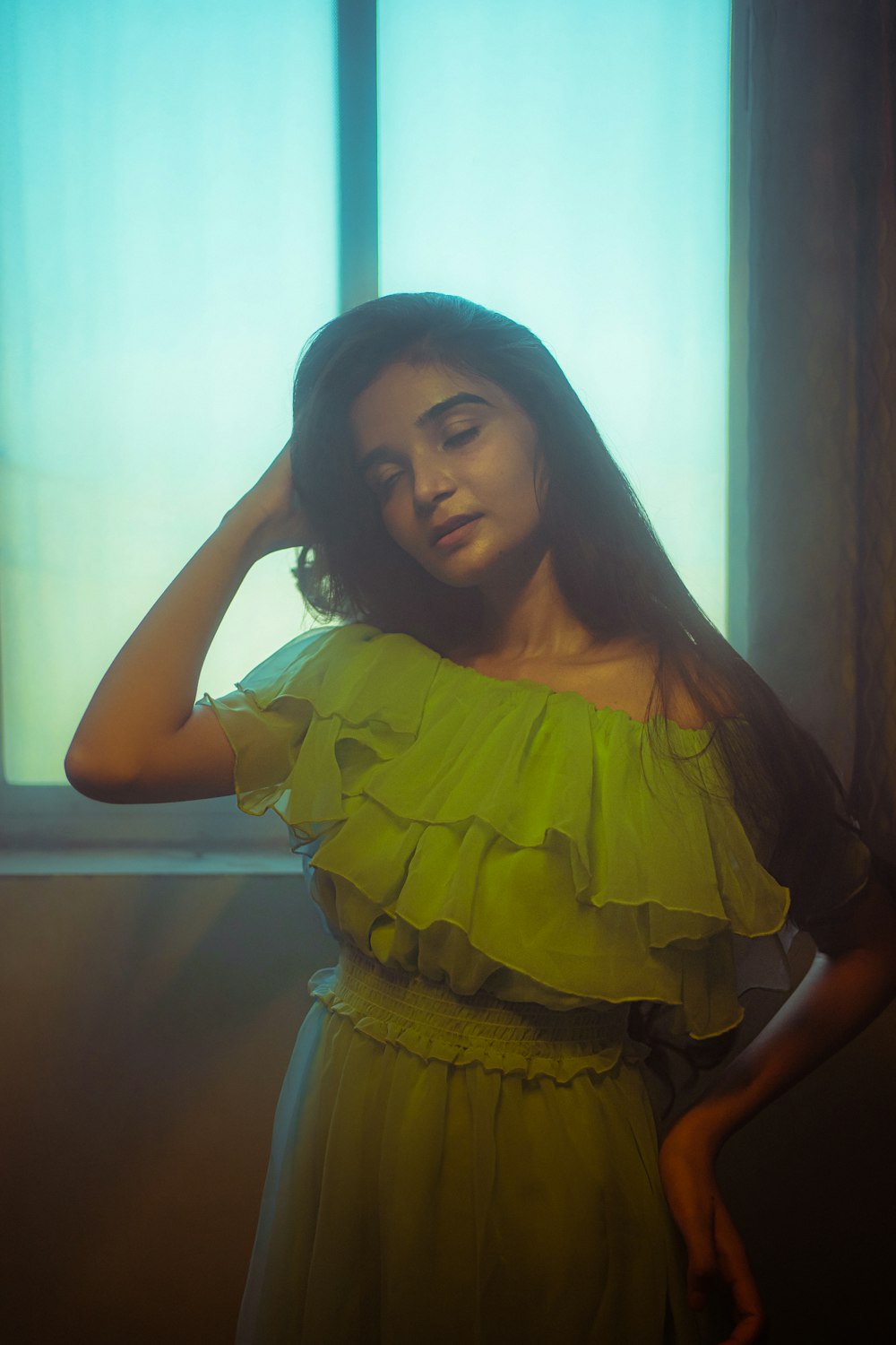 a woman in a green dress standing in front of a window