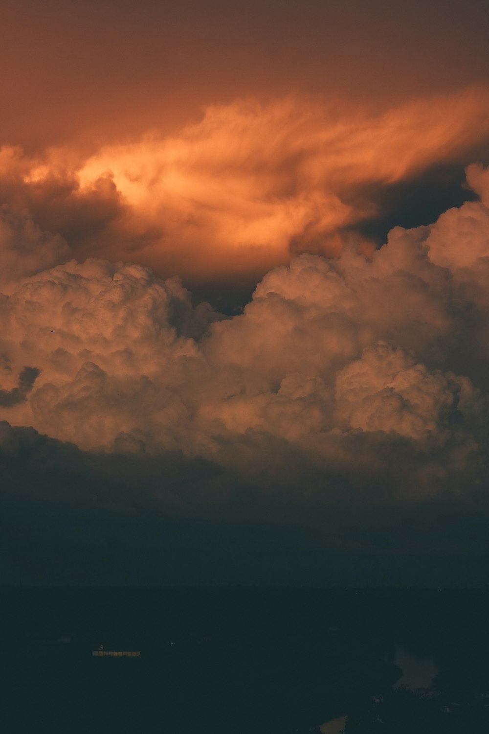 a plane flying through a cloudy sky at sunset