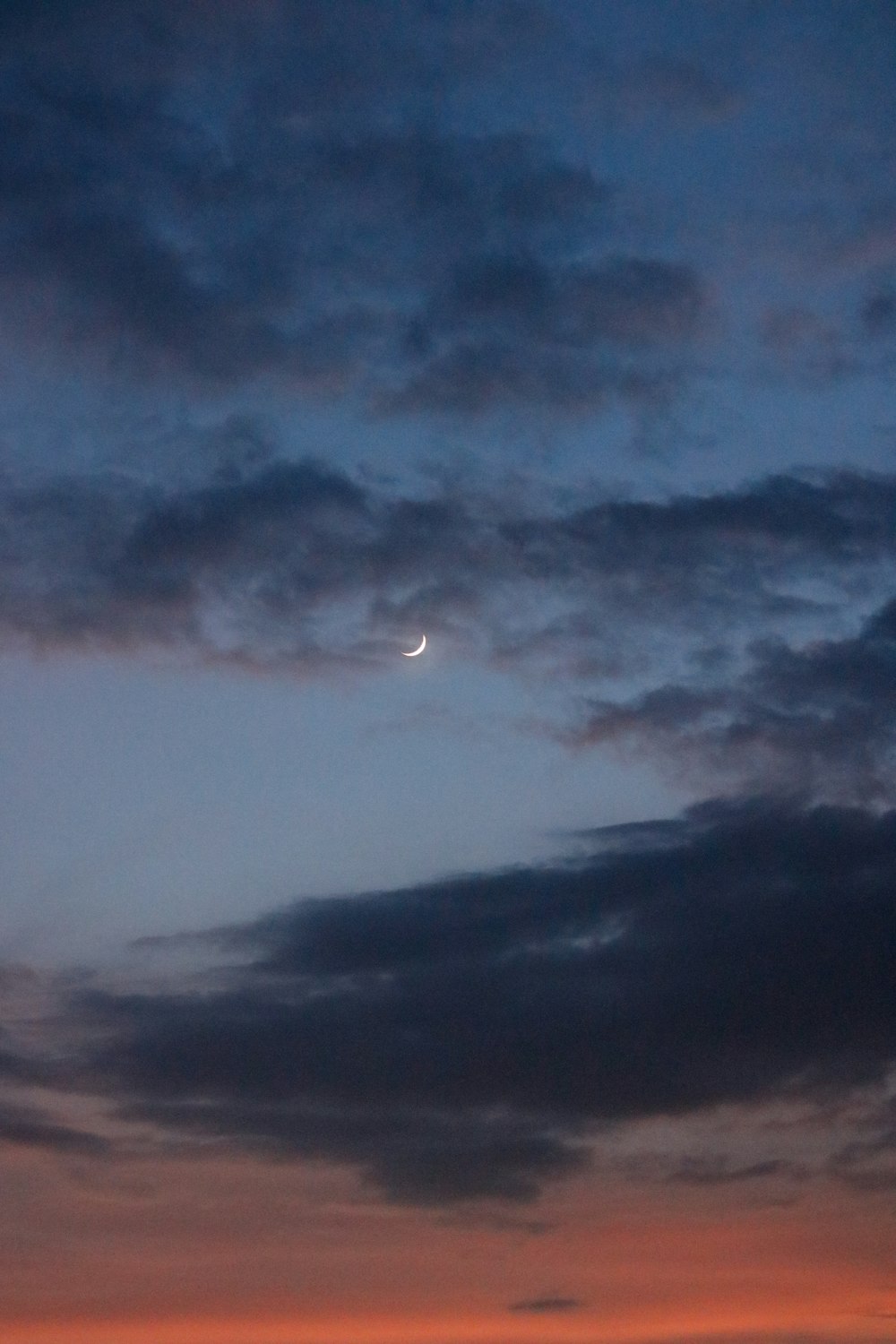 Blick auf einen Sonnenuntergang mit dem Mond in der Ferne