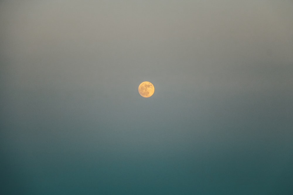a full moon is seen in the sky over the ocean