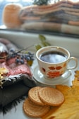 A cozy kitchen scene with a plate of biscuits and gravy next to a steaming cup of coffee.