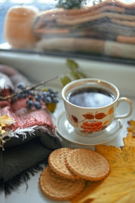 A cozy kitchen scene with a plate of biscuits and gravy next to a steaming cup of coffee.