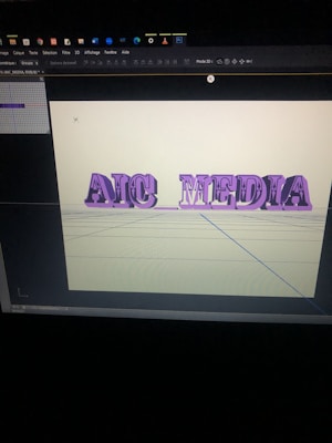 A computer screen displaying a 3D modeling software with the words 'AIC MEDIA' in purple, extruded text. The background is a pale yellow with grid lines visible on the virtual floor.