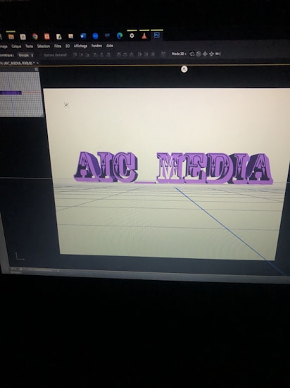 A computer screen displaying a 3D modeling software with the words 'AIC MEDIA' in purple, extruded text. The background is a pale yellow with grid lines visible on the virtual floor.