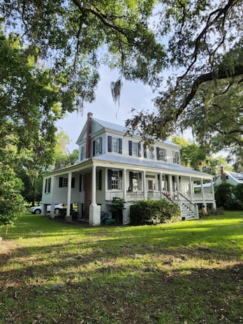 A cozy, restored historic home surrounded by lush greenery and a welcoming porch.