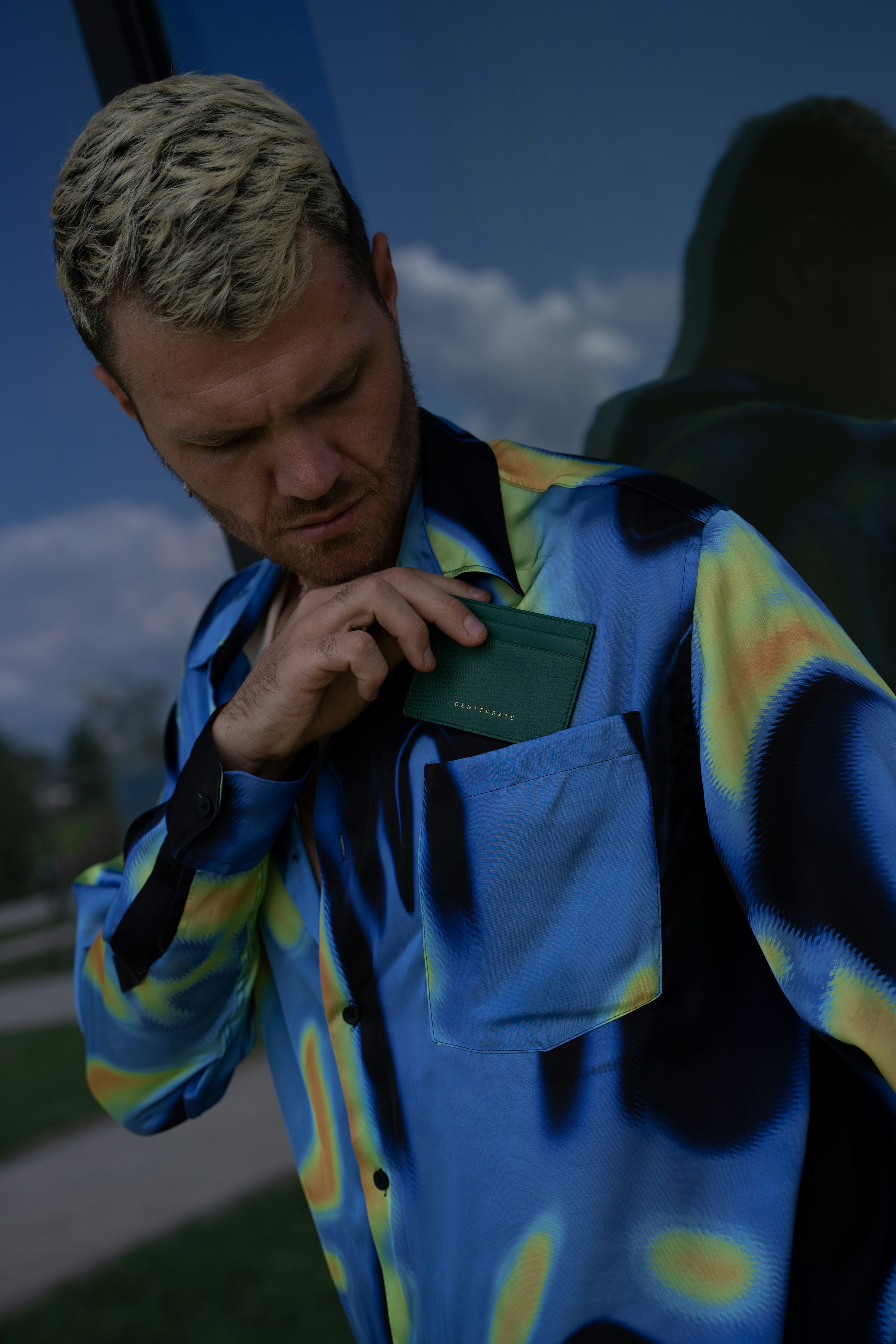 a man in a blue and yellow shirt holding a green card