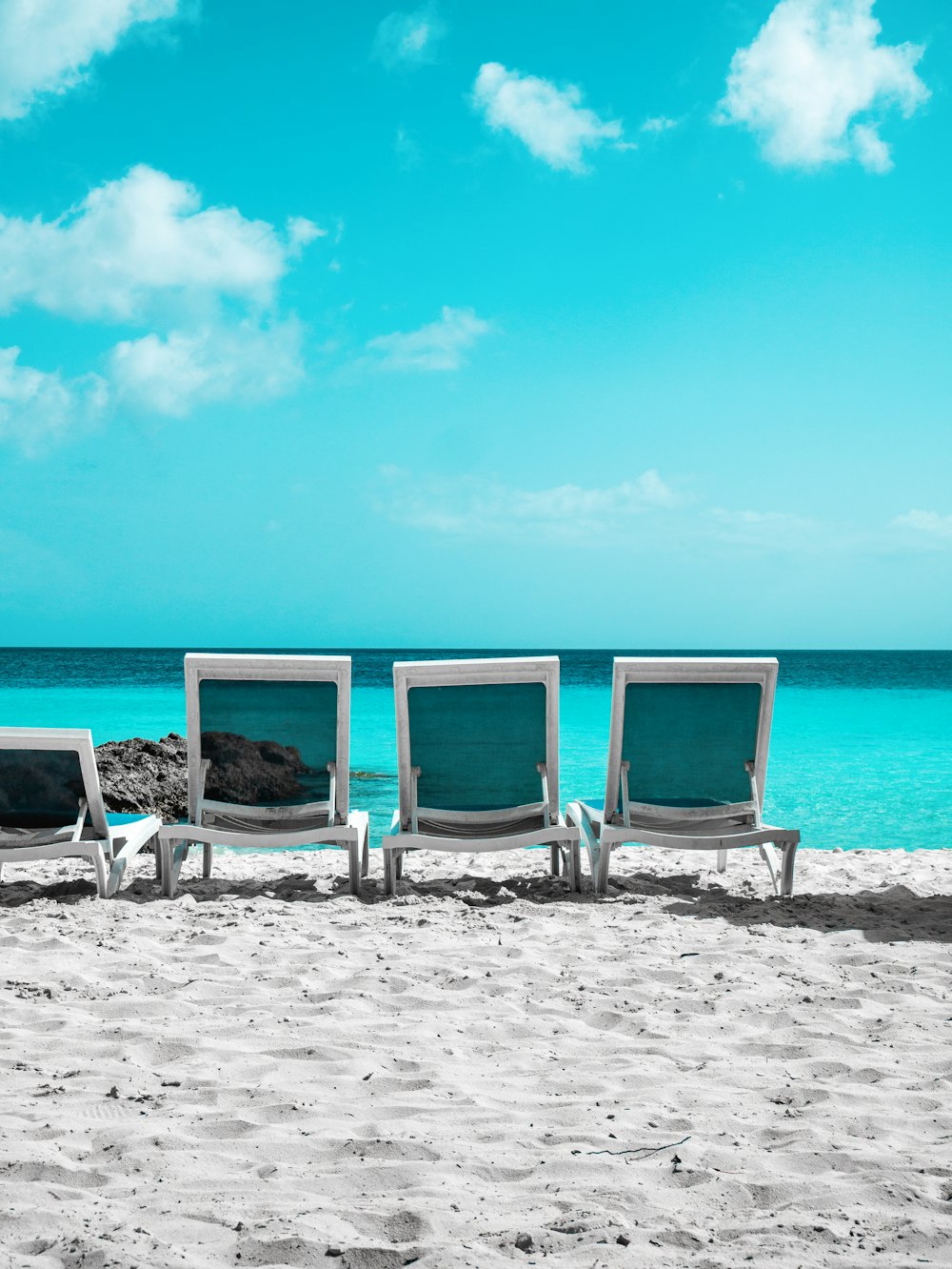 a row of chairs sitting on top of a sandy beach