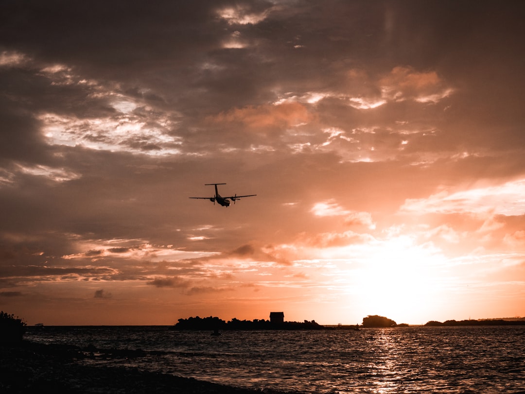 a plane flying over a body of water at sunset,